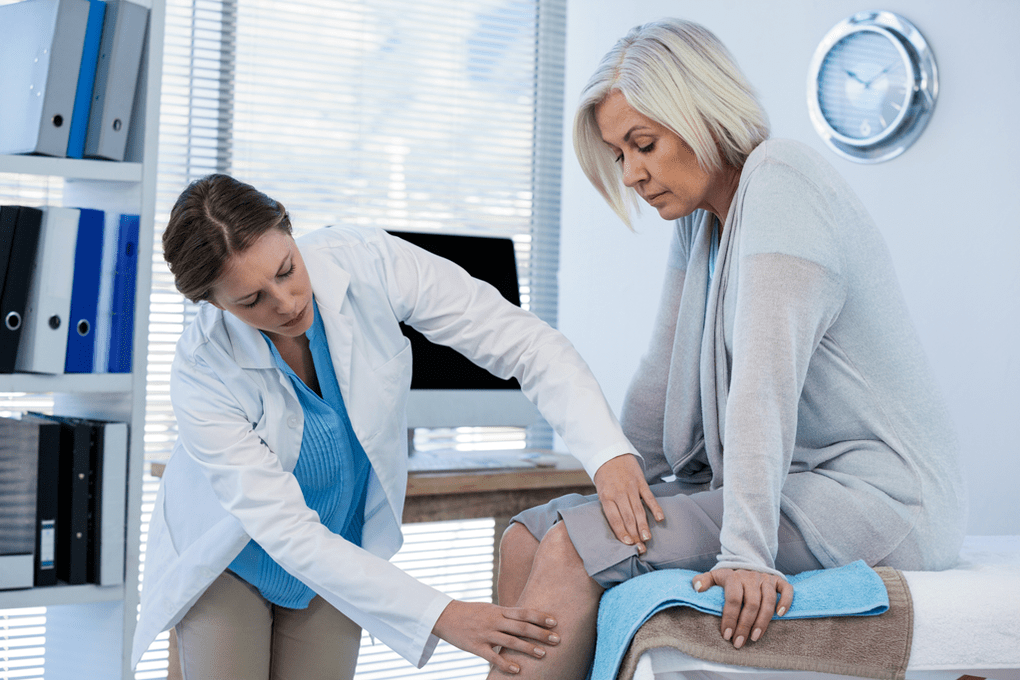 Medicul examinează un pacient cu artroză a articulației genunchiului